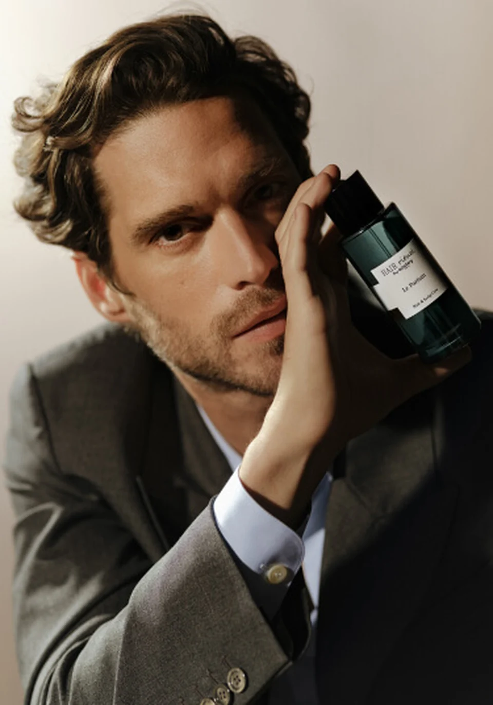 Male model holding the Hair Rituel by Sisley Le Parfum bottle